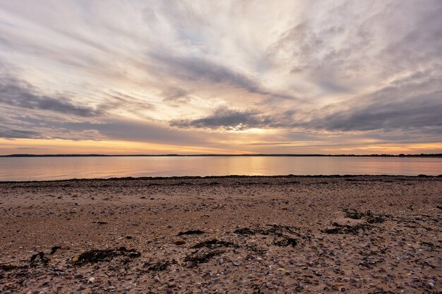 Piękne ujęcie spokojnego oceanu z scenerią zachodu słońca w pochmurne błękitne niebo