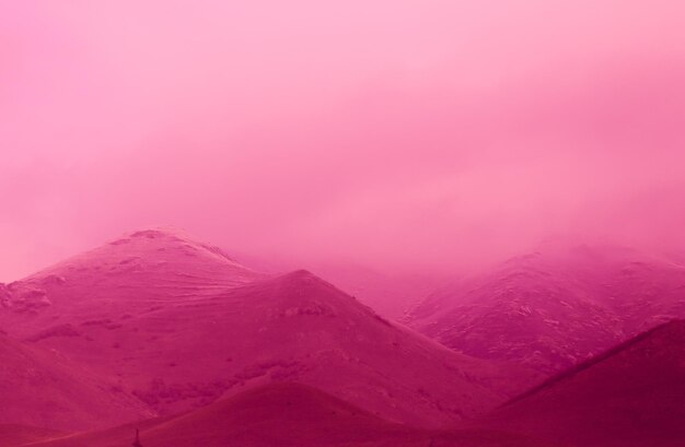 Piękne ujęcie wzgórz pokrytych mgłą w różowym odcieniu