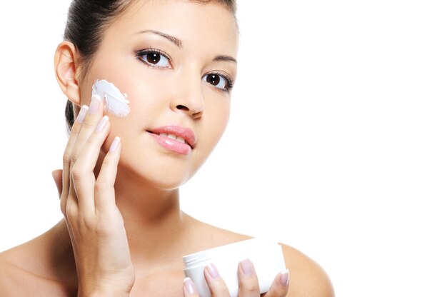 Piękno azjatyckiej kobiecej skóry twarzy, nakładając krem kosmetyczny na policzek