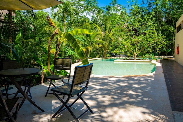 Piękny basen pośród bujnej zieleni z krzesłami i stołem w luksusowym ośrodku hotelowym. spokojny basen w ośrodku?