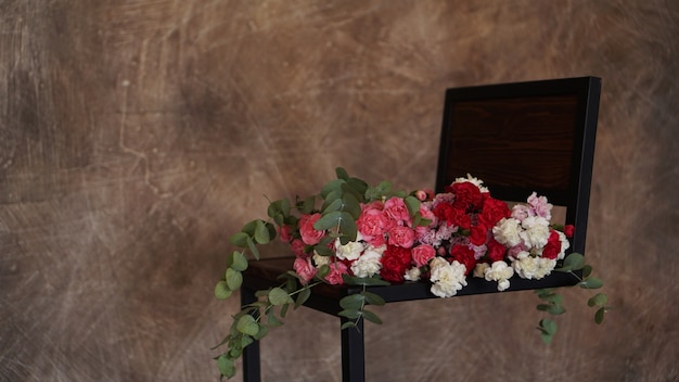 Piękny Bukiet Różowych I Białych Goździków. Bukiet Z Zielonymi Gałązkami Leży Na Ciemnym Tle Z Teksturą Premium Zdjęcia