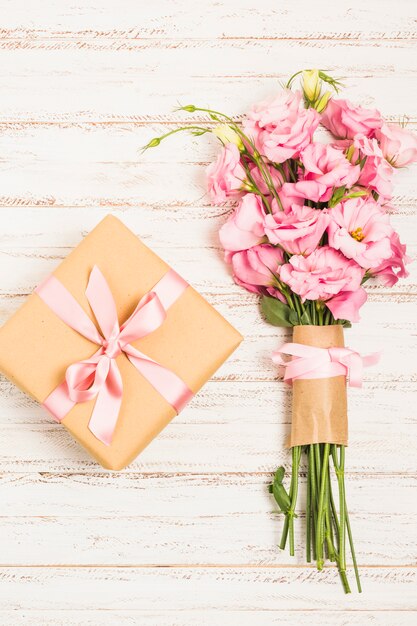 Piękny bukiet świeżych różowych eustoma kwitnie z teraźniejszości pudełkiem na drewnianej powierzchni