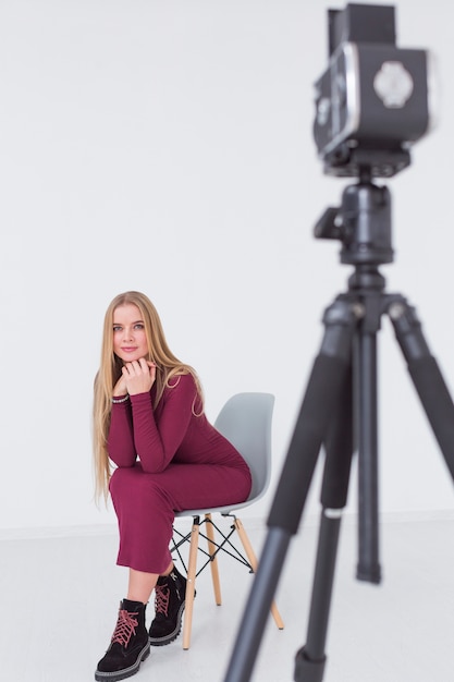 Piękny kobieta modela obsiadanie na krześle w studiu i kamerze