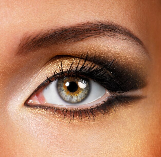 Piękny kształt kobiecego oka ze złotobrązowym makijażem kosmetycznym