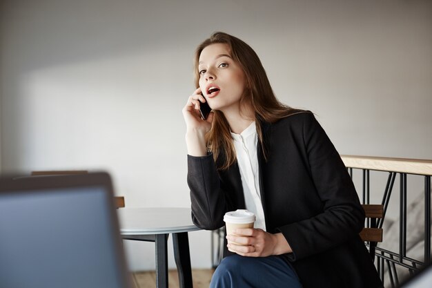 Piękny młody bizneswoman opowiada telefonem w kawiarni