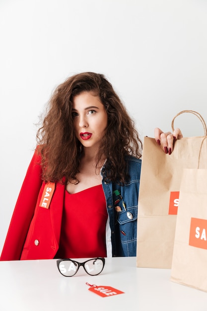 Bezpłatne zdjęcie piękny młody sprzedaży kobiety obsiadanie z papierowymi torba na zakupy