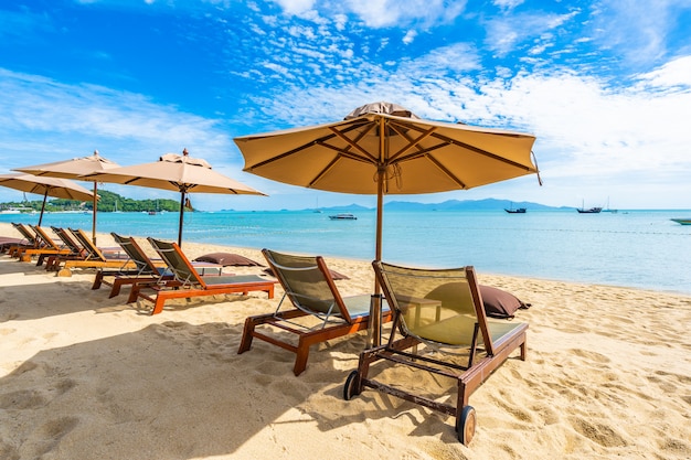 Piękny tropikalny plażowy morze, ocean z kokosowym drzewkiem palmowym, parasol i krzesło na niebieskim niebie