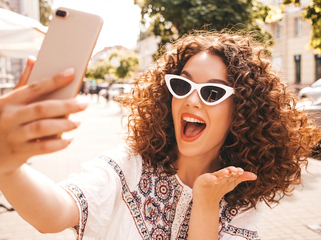 Piękny uśmiechnięty model z fryzurą afro loki, ubrany w letnią białą sukienkę hipster.