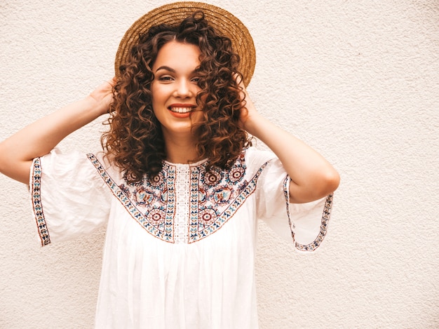 Piękny uśmiechnięty model z fryzurą afro loki, ubrany w letnią białą sukienkę hipster.