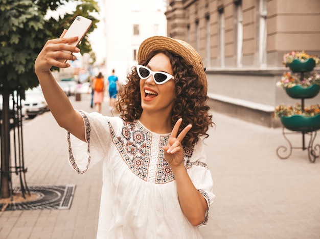 Piękny uśmiechnięty model z fryzurą afro loki, ubrany w letnią białą sukienkę hipster.