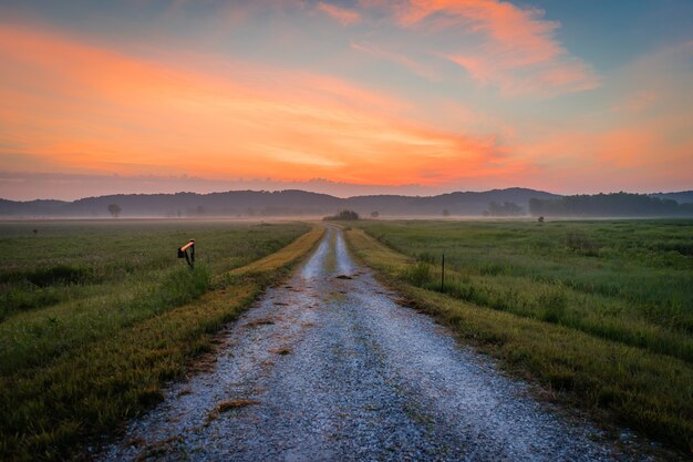 Piękny widok na drogę biegnącą przez pola pod zapierającym dech w piersiach kolorowym niebem