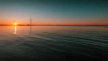 Bezpłatne zdjęcie piękny widok na spokojny ocean z turbinami pod hipnotyzującym zachodem słońca w
