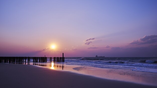 Piękny widok na zachód słońca z fioletowymi chmurami nad plażą