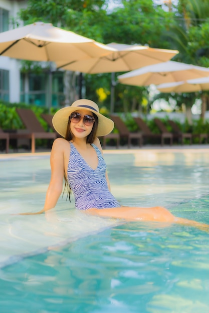 Pięknych młodych azjatykcich kobiet szczęśliwy uśmiech relaksuje wokoło plenerowego pływackiego basenu w hotelowym kurorcie