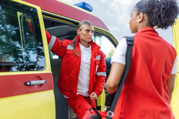 Pielęgniarka i lekarz pogotowia ratunkowego w karetce pogotowia z zestawem sanitariusz stojący z tyłu karetki przy otwartych drzwiach