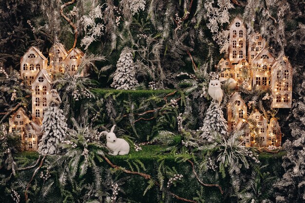 Pień fotografia pięknego ręcznie robionego lasu jodłowego i tekturowych budynków oświetlonych girlandami i dekoracyjnymi zabawkami sowy i królika.