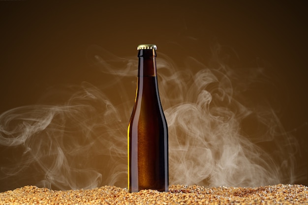 Pij serię makiety. brązowa butelka piwa z odbiciami, które stoi na zbożu pszenicy na tle studio umbra z lekkim dymem. szablon gotowy do użycia w swoim projekcie.