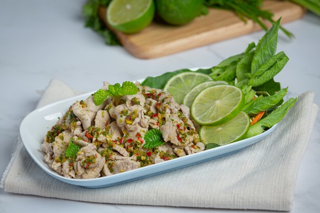 Pikantna Sałatka Wieprzowa Podawana ze świeżymi, chrupiącymi łodygami jarmużu tajskie jedzenie.