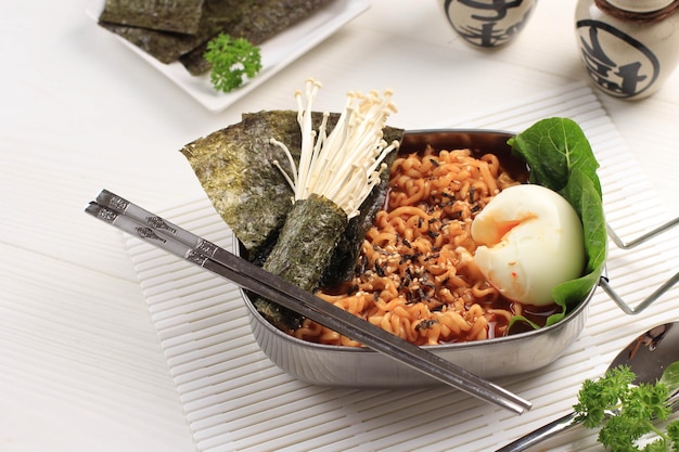 Pikantny koreański instant ramen lub ramyun z jajkiem na miękko, pieczarkami i nori laver. zwieńczona sezamem