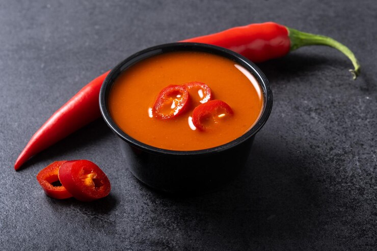 Bezpłatny plik Zdjęcie pikantny sos chili w misce na czarnym tle