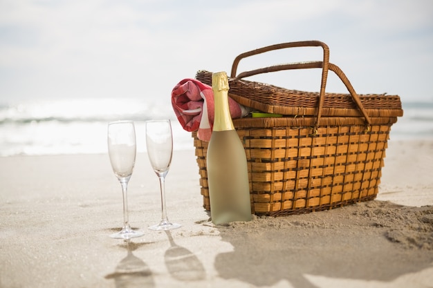 Piknik kosz, butelka szampana i dwa kieliszki na piasku