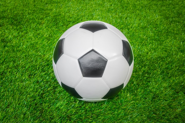 Piłka nożna na zielonej trawie.
