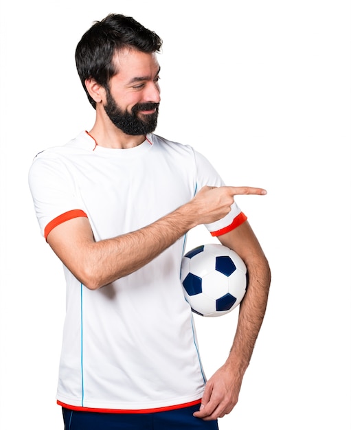 Piłkarz trzyma piłkę nożną skierowaną do boku