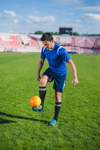 Bezpłatne zdjęcie piłkarz żonglerka piłkę na stadionie