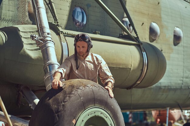 Pilot lub mechanik w mundurze i hełmie latającym myje duży śmigłowiec wojskowy.