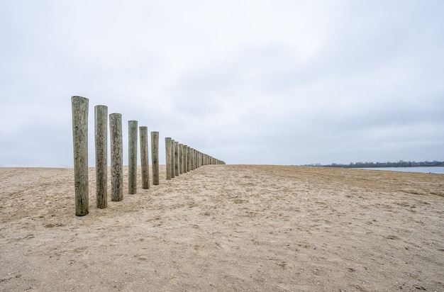 Pionowe drewniane deski niedokończonego pokładu na plaży pod zachmurzonym niebem