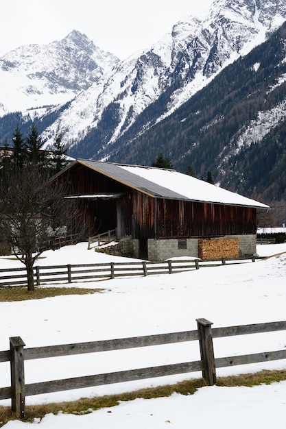 Pionowe ujęcie drewnianej chaty pokrytej śniegiem i górami w zimie