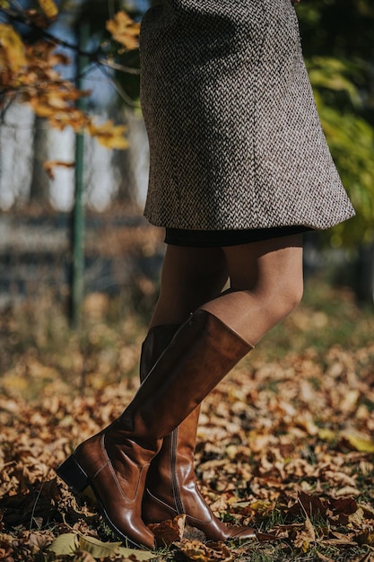 Bezpłatne zdjęcie pionowe ujęcie kobiety noszącej modne brązowe skórzane buty do kolan na zewnątrz