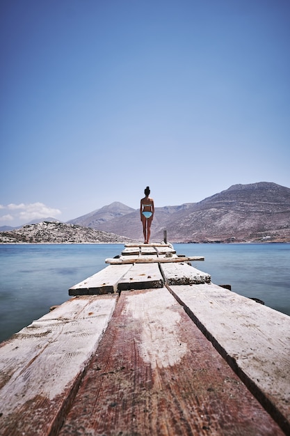 Pionowe ujęcie kobiety stojącej na skraju drewnianego doku na wyspie Amorgos, Grecja