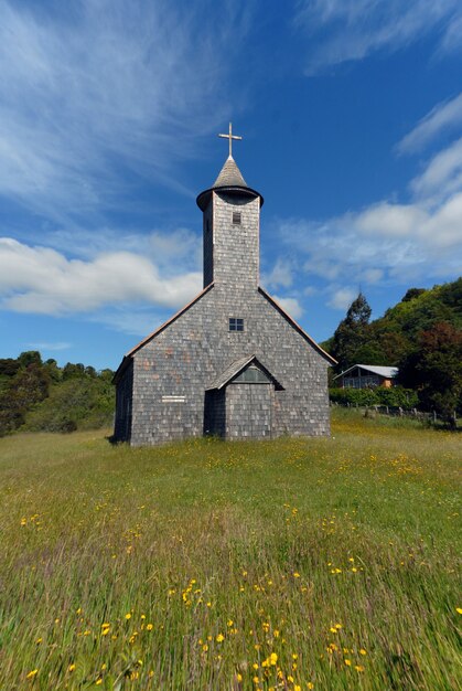 Pionowe ujęcie kościoła w trawiastym polu pod błękitnym niebem