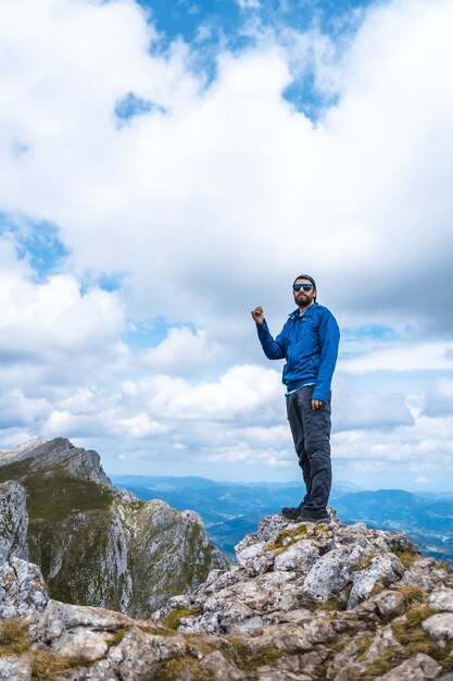 Pionowe ujęcie mężczyzny stojącego na szczycie góry Aitzkorri w Gipuzkoa