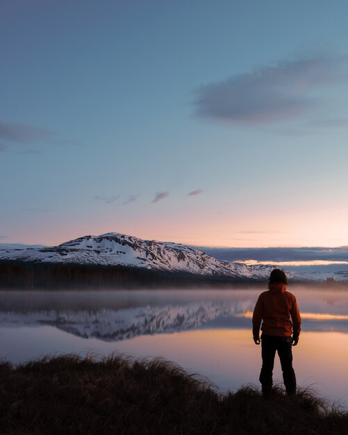 Pionowe ujęcie mężczyzny stojącego przed pięknym krajobrazem