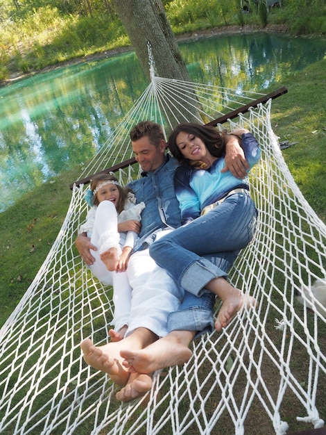 Pionowe ujęcie ojca, matki i córki leżących na hamaku w ogrodzie