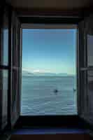 Bezpłatne zdjęcie pionowe ujęcie otwartego okna z widokiem na piękne morze