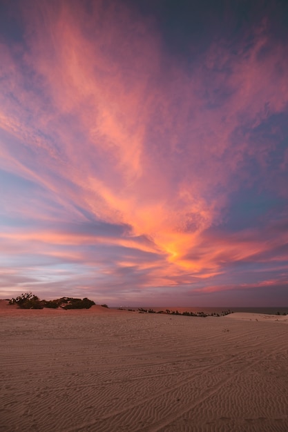 Pionowe ujęcie piaszczystych wzgórz pod zapierającym dech w piersiach kolorowym niebem w północnej Brazylii