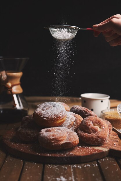 Pionowe ujęcie pysznych pączków węża posypane cukrem pudrem i kawą chemex