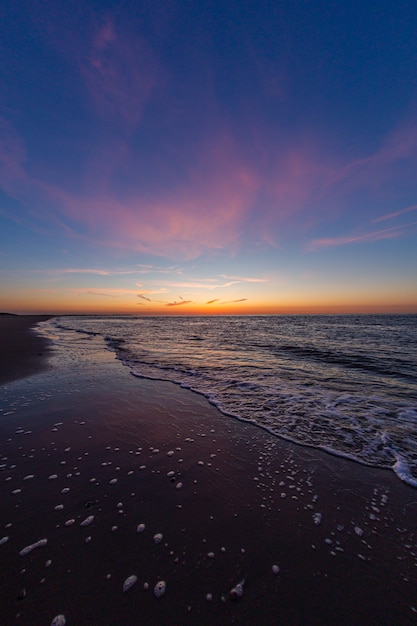 Pionowe ujęcie spokojnego oceanu podczas zachodu słońca w Vrouwenpolder, Zeeland, Holandia