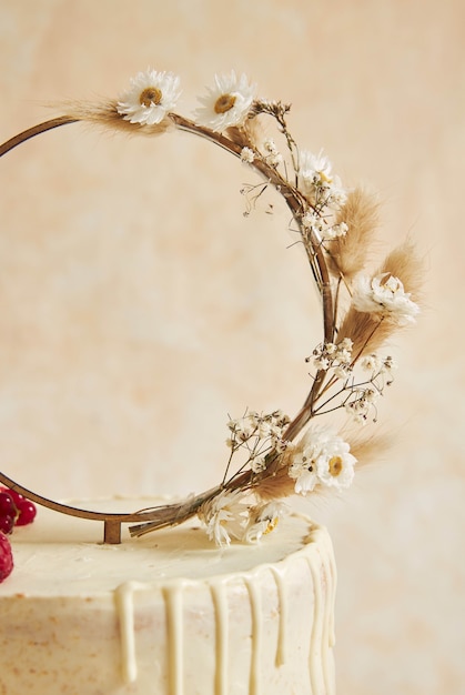 Bezpłatne zdjęcie pionowe ujęcie tortu weselnego ozdobionego świeżymi owocami i jagodami oraz pierścionkiem z kwiatów