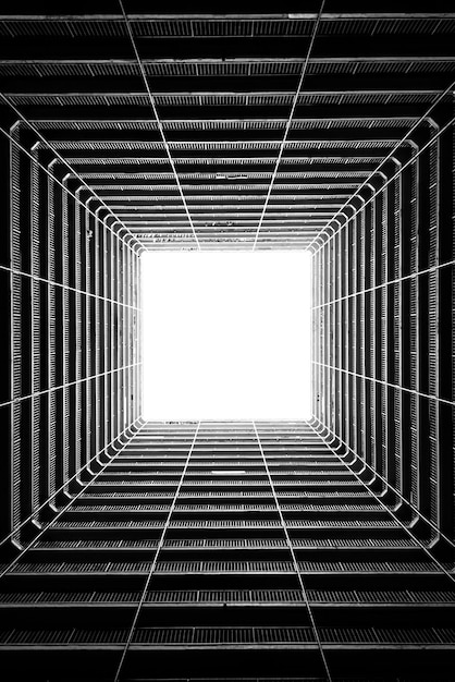 Bezpłatne zdjęcie pionowe ujęcie w skali szarości pod niskim kątem światła wpadającego przez sufit wysokiego budynku