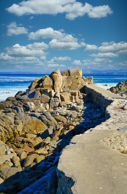 Pionowe ujęcie wielu formacji skalnych na plaży pod pięknym pochmurnym niebem