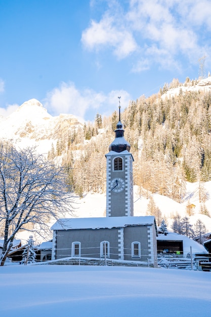 Bezpłatne zdjęcie pionowe ujęcie wieży zegarowej z pokrytymi śniegiem górami