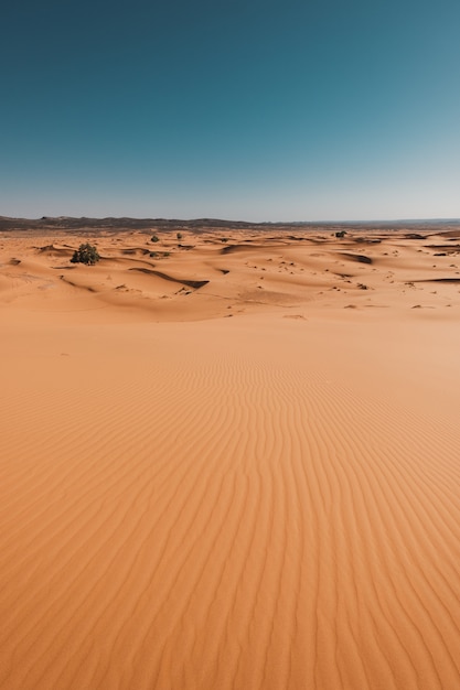 Pionowe ujęcie zapierającej dech w piersiach pustyni pod błękitne niebo uchwycone w Maroku