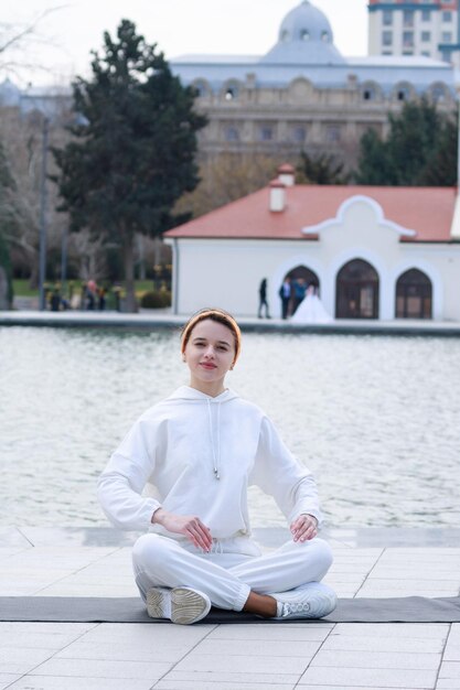 Pionowe zdjęcie młodej damy medytującej w parku nad jeziorem Zdjęcie wysokiej jakości