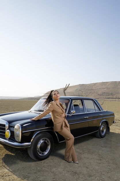 Pionowe zdjęcie młodej pięknej dziewczyny z samochodem na pustyni Wysokiej jakości zdjęcie