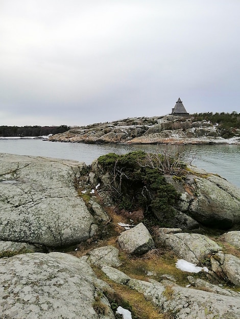 Pionowy obraz skał otoczonych rzeką pod zachmurzonym niebem w Norwegii