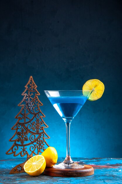 Bezpłatne zdjęcie pionowy widok koktajlu alchocolowego w szklanym kielichu podawanym z plasterkiem cytryny i choinką na niebieskim tle
